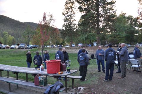 A group of people wearing Forum sweatshirts stand together near picnic tables outdoors.